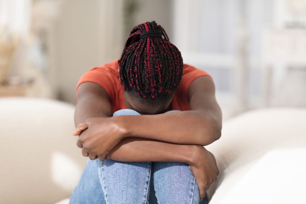 woman sitting on the head on her knees on the couch wondering how do you know if you're having a nervous breakdown